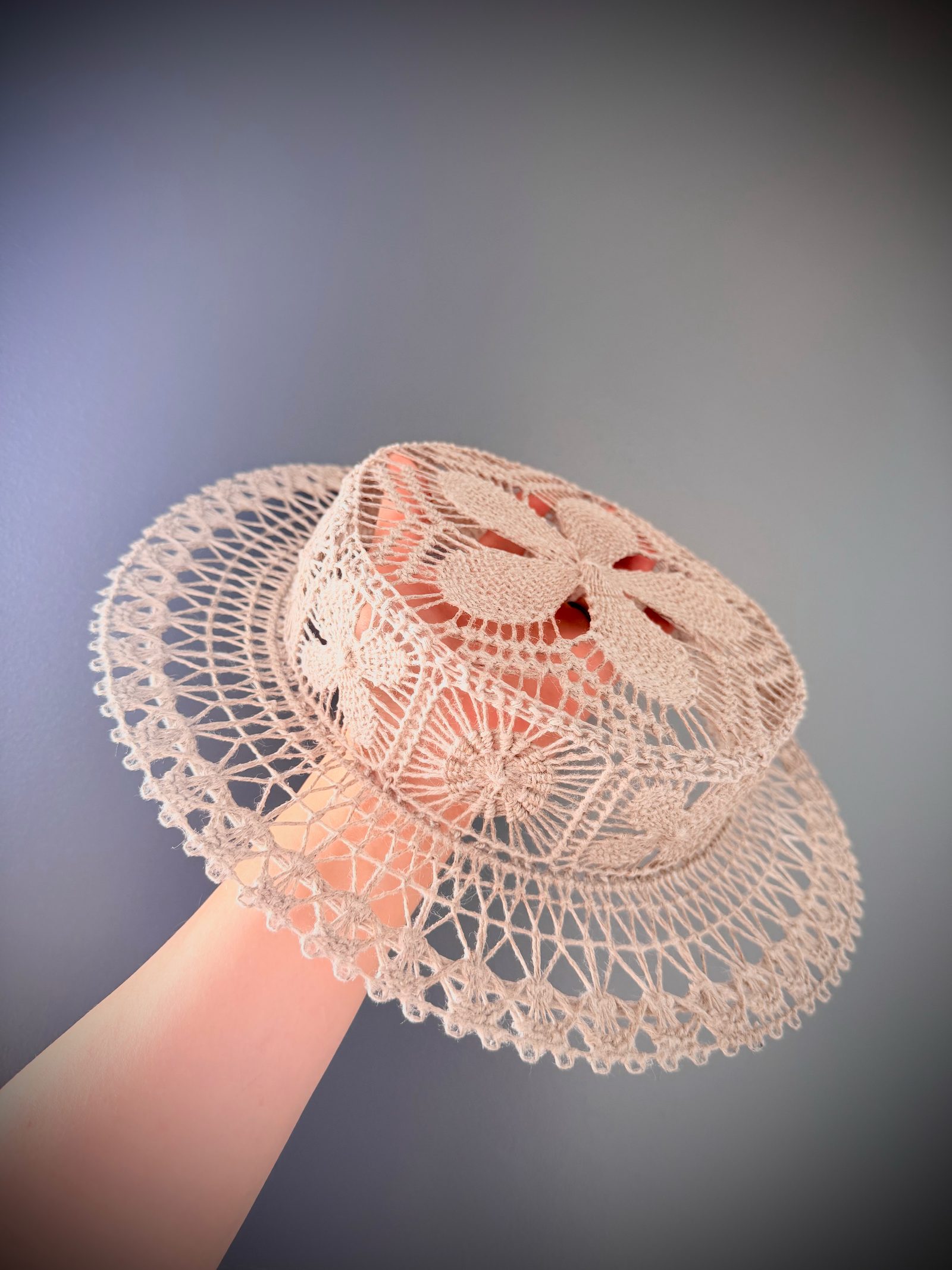 A ramie Ñandutí canotier held to the light, the lace almost transparent.