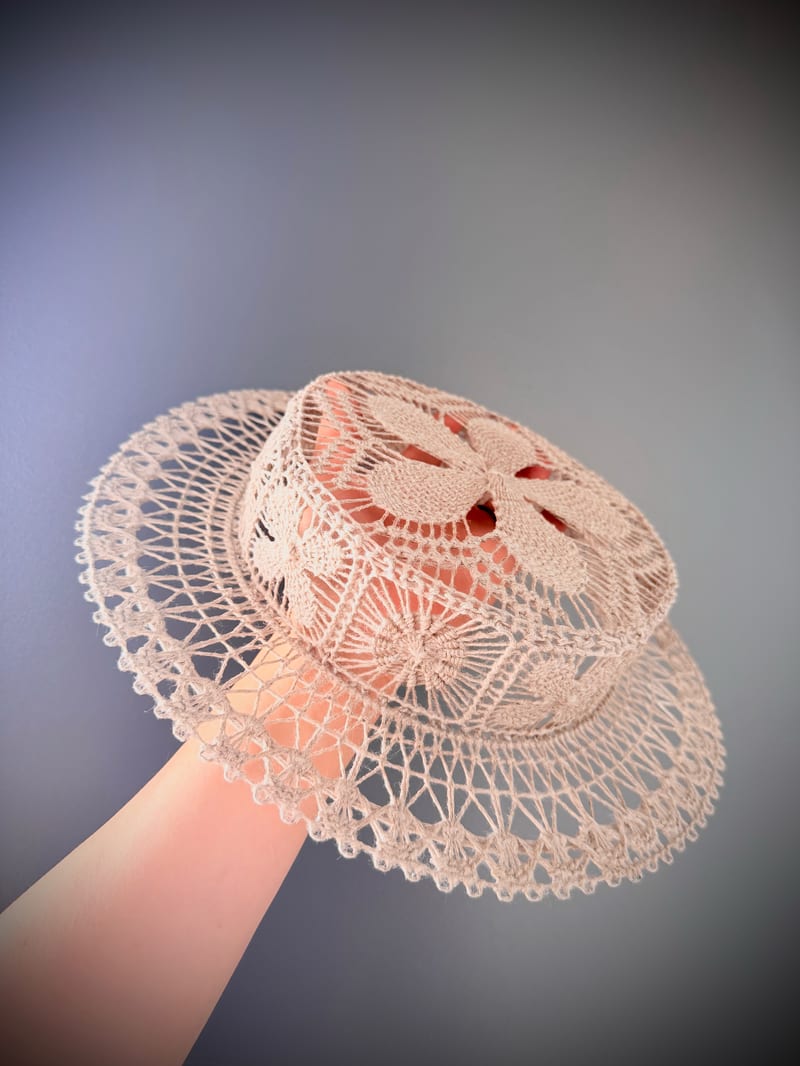 A ramie Ñandutí canotier held to the light, the lace almost transparent.